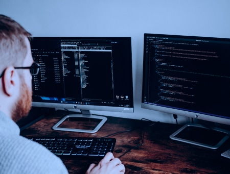 Image of a man looking at the screens displaying codes