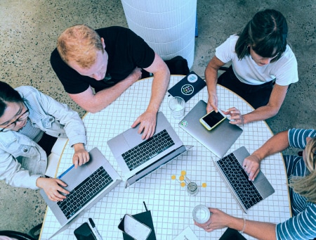 image of a group of people gathered around with laptops in fron of them