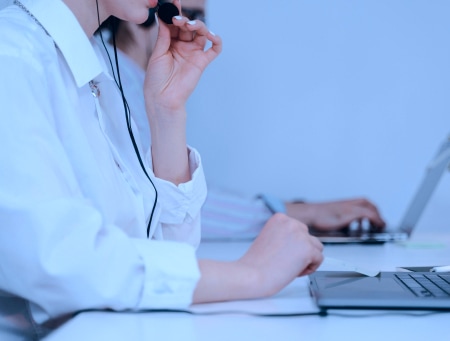 Image of a woman in front of a laptop using a headset to speak with someone